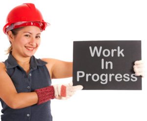 Work In Progress Sign Held By Construction Worker