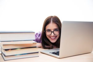 Woman sitting at the table with laptop and books