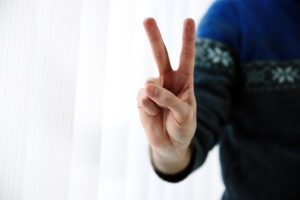 Closeup portrait of a male hand with two fingers up in the peace or victory symbol